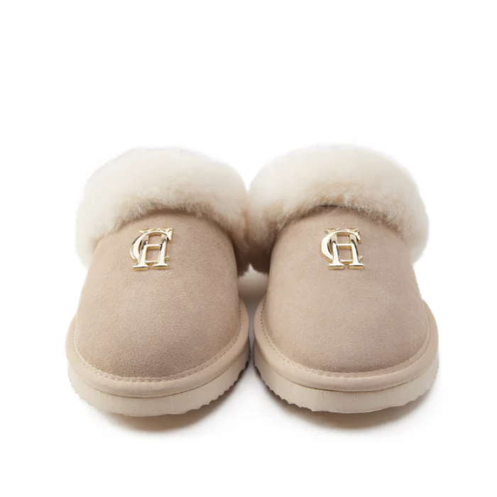 Pair of beige slippers with fur trim on a white background