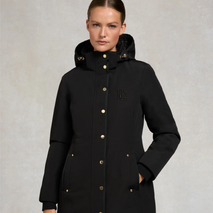 Woman wearing a black coat with a brand logo on a light gray background