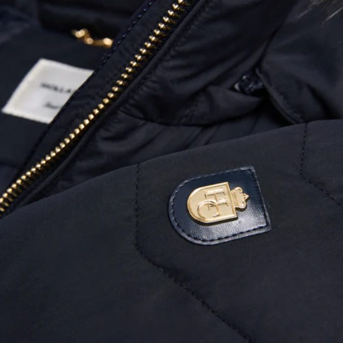 Close-up of a navy blue jacket with a gold emblem and brand label.