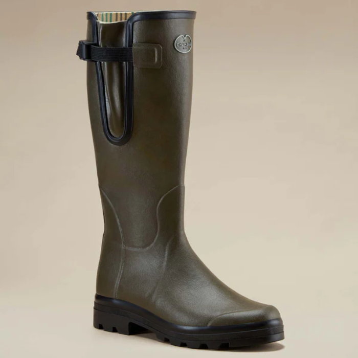 Green rubber boot with a black strap on a beige background