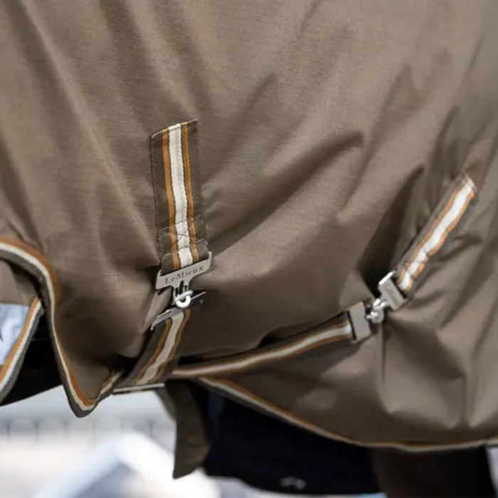 Close-up of a brown horse blanket with a brand label on a blurred background