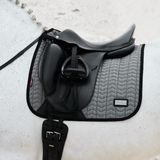 Black saddle with a grey saddle pad with a textured surface