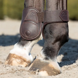Horse leg with protective boot on a sandy ground