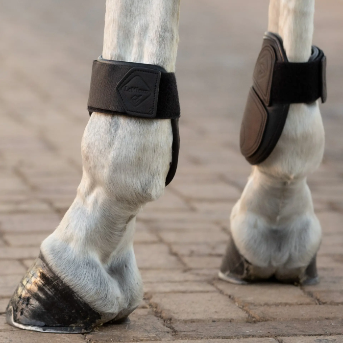 Horse hooves with protective boots on a brick surface