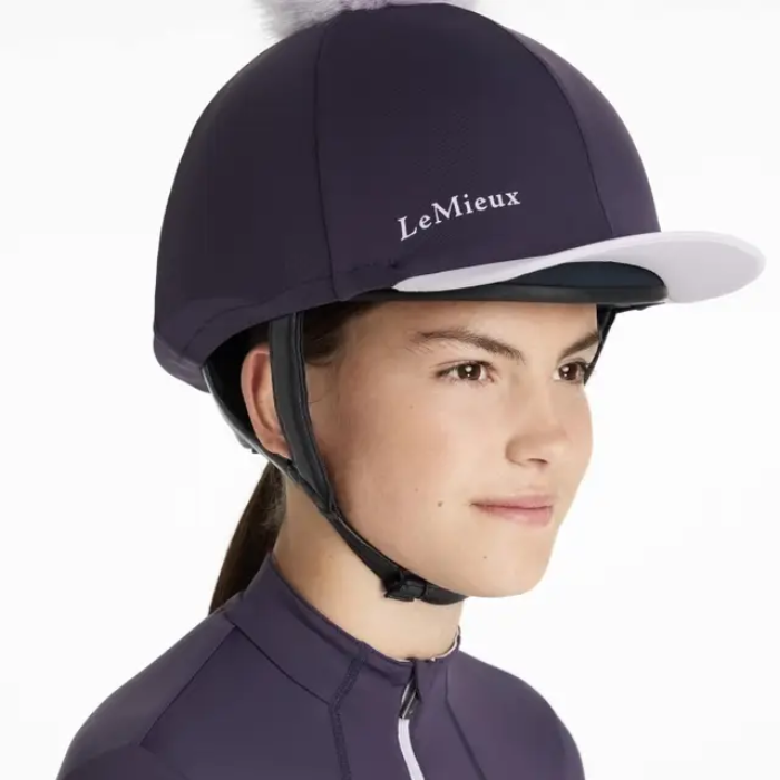 Person wearing an equestrian helmet with purple cover and 'LeMieux' branding on a white background