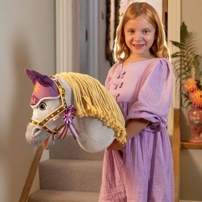 Young girl in a purple dress holding a decorative horse toy indoors.