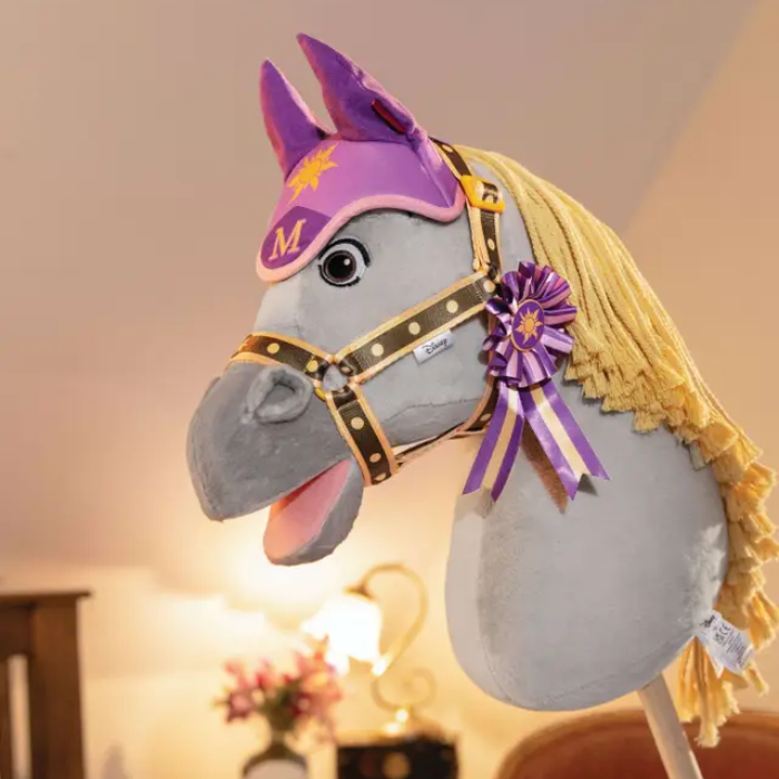 Plush toy horse with purple and yellow accents in a softly lit room.