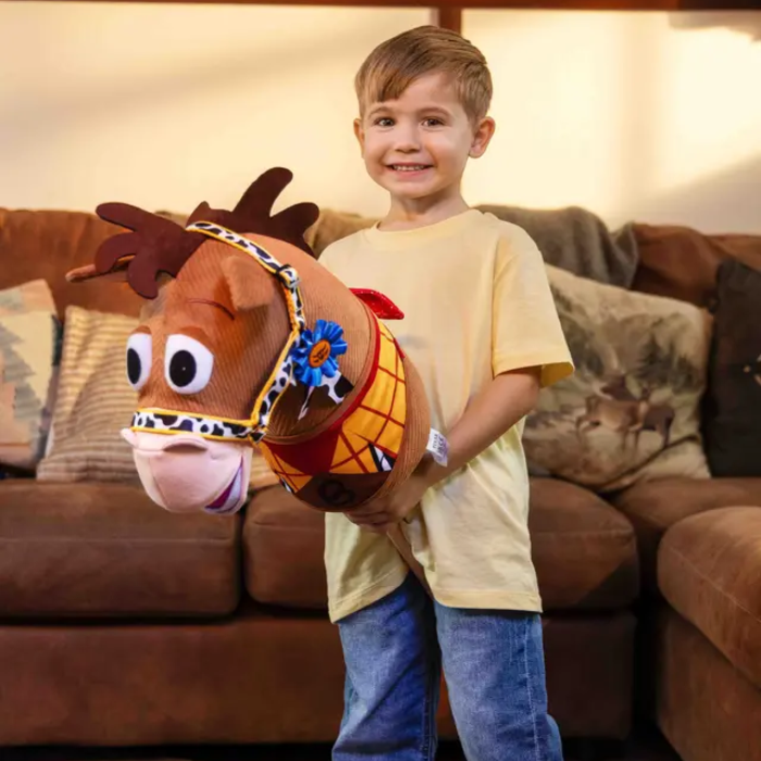 Child holding a plush toy horse in a living room setting