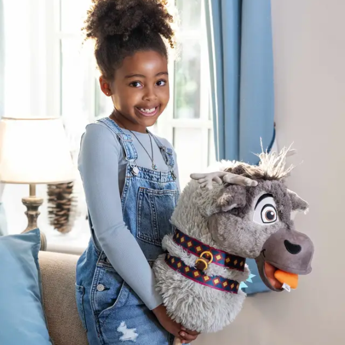 Young girl holding a plush reindeer toy in a living room setting