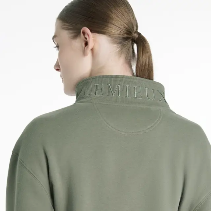 Person wearing a green sweater with 'LEMIEUX' branding on the back on a white background
