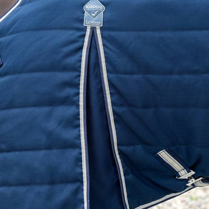 Close-up of a blue quilted horse rug with a brand tag on a blurred background