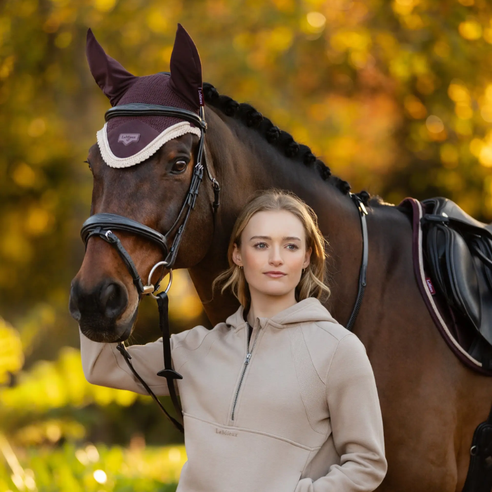 Woman standing next to a horse in an outdoor setting with trees in the background