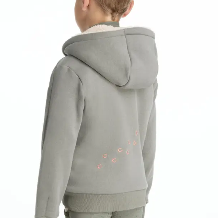 Child wearing a light green hoodie with decorative hoof print elements on a white background