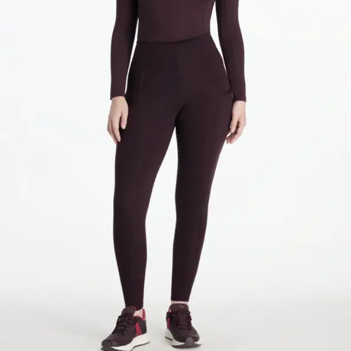 Person wearing dark purple riding leggings and a matching top on a white background