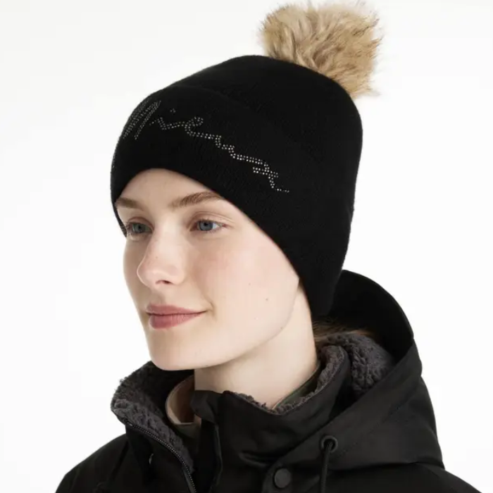 Person wearing a black beanie with a fur pom-pom and a black coat on a white background