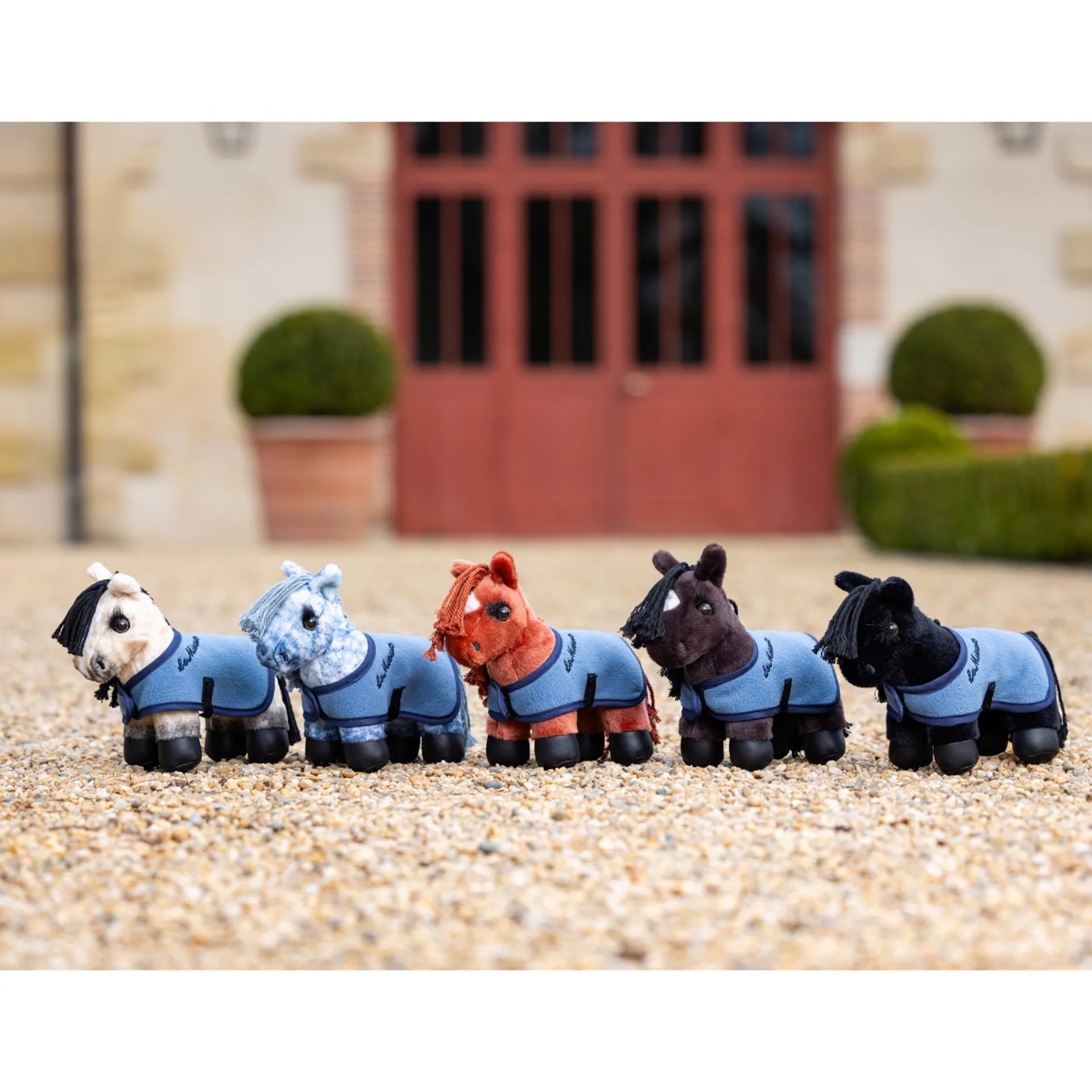 Plush toy ponies lined up on gravel floor