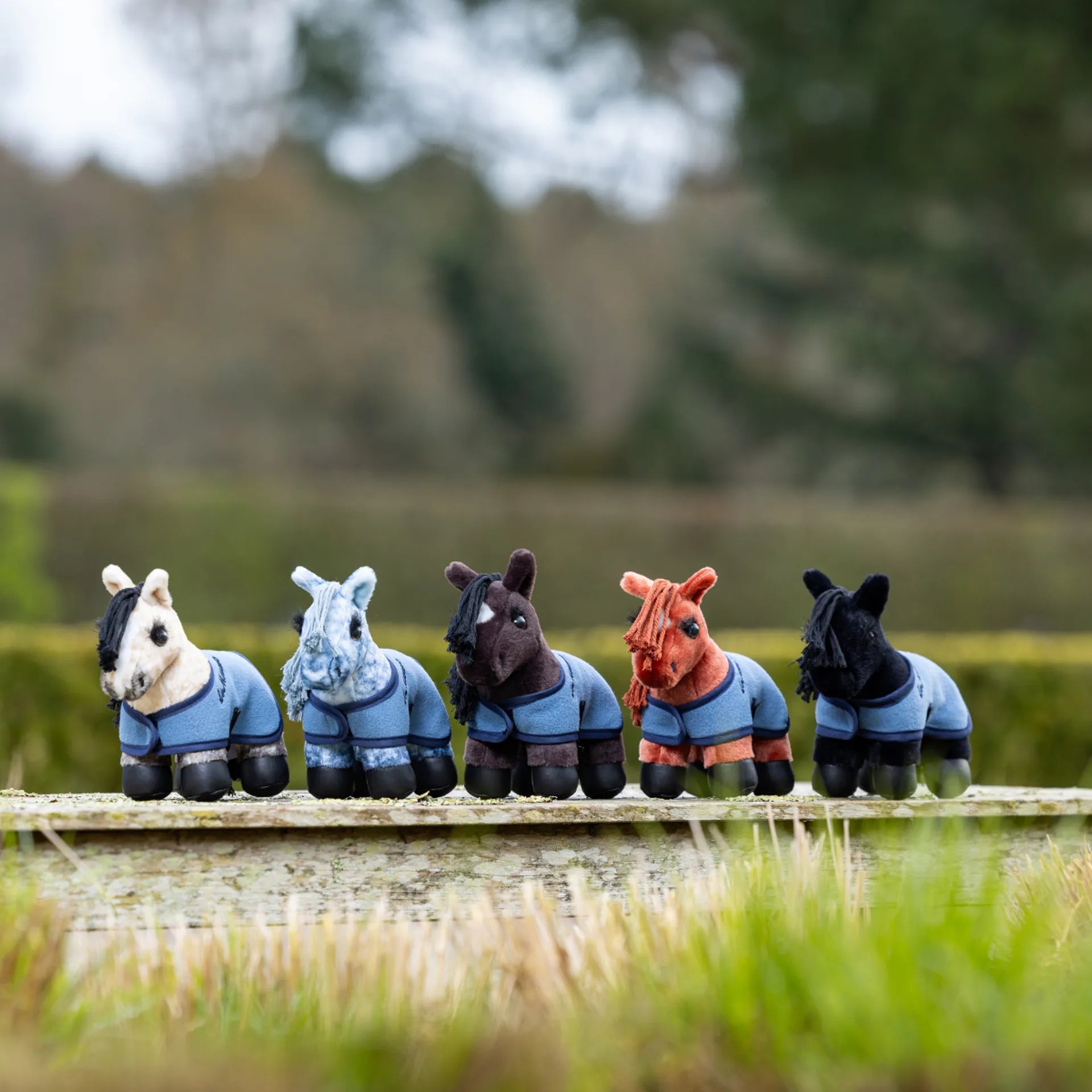 Plush toy ponies lined up on a wooden fence