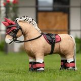 Plush toy horse with a red and black bridle on grass