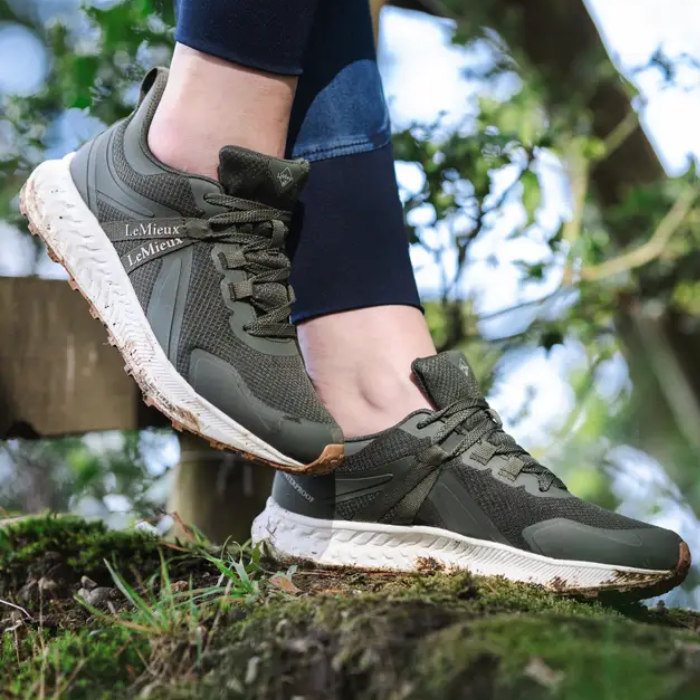Person wearing green athletic shoes with 'LeMieux' branding on a natural background