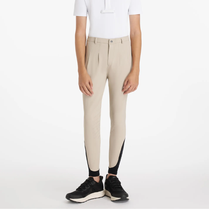 Person wearing beige breeches with black accents on a white background