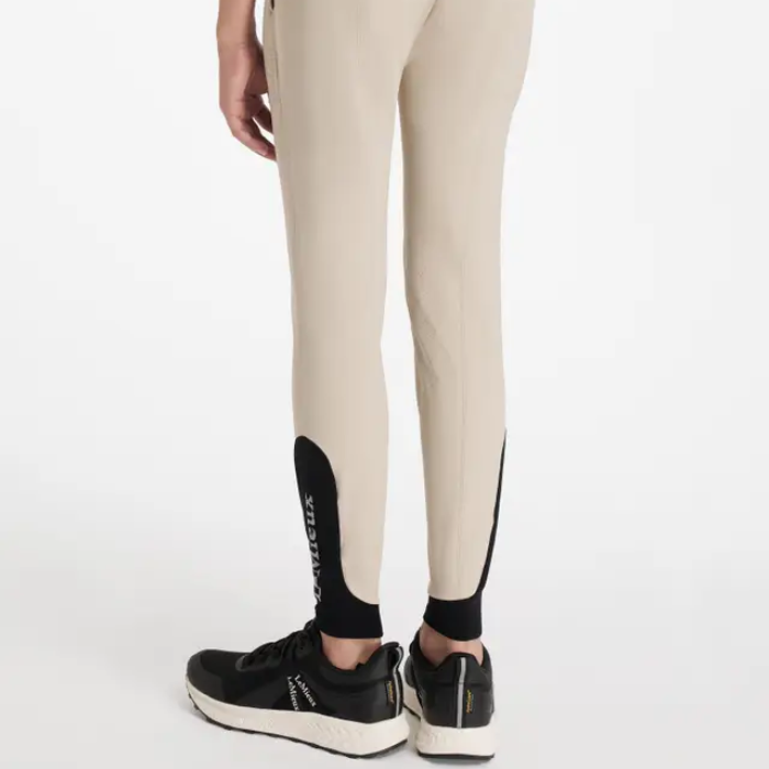 Beige breeches with black accents worn by a person on a white background