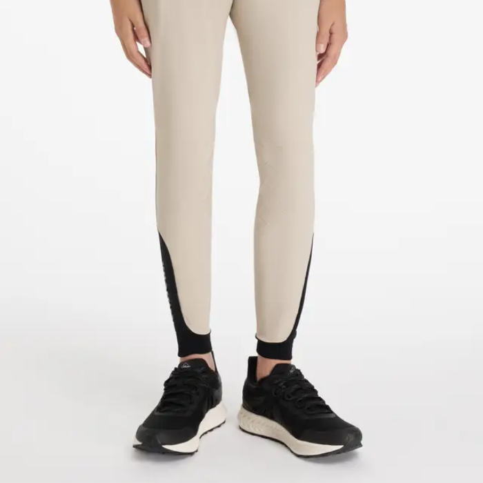 Beige breeches with black accents worn by a person on a white background