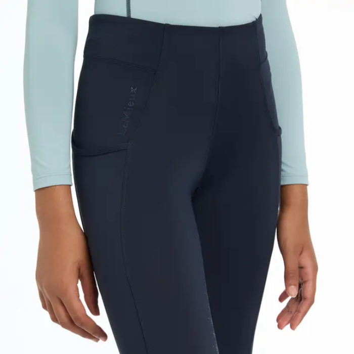 Navy riding leggings with a light blue long-sleeve top on a white background