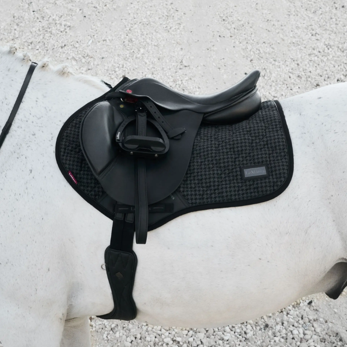 Black saddle on a white horse with a gravel background