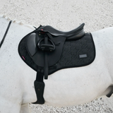 Black saddle on a white horse with a gravel background