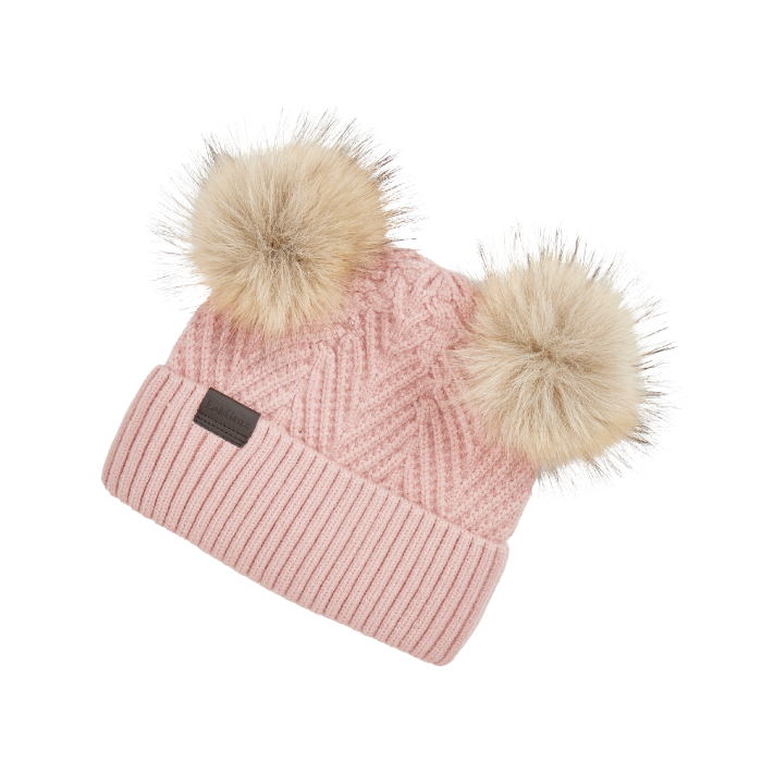 LeMieux AW26 Mini Double Pom Beanie Variant Colour Petal.
A light pink cable-knit beanie hat featuring two large beige faux-fur pom-poms on top and a small dark brown rectangular brand patch on the front cuff.