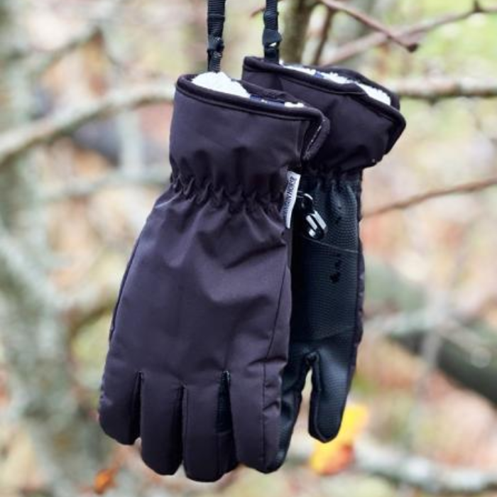 Black gloves hanging on a branch with a blurred natural background