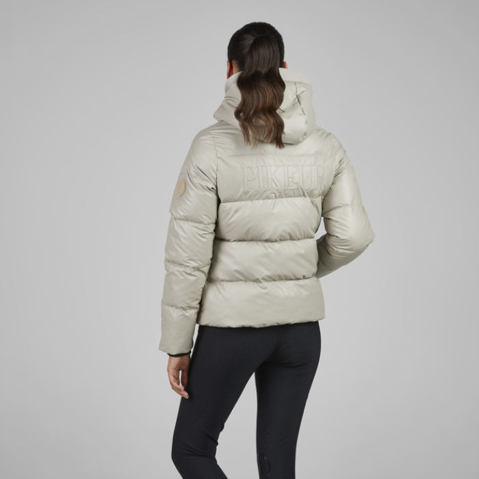 Person wearing a beige puffer jacket on a grey background
