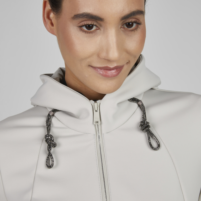 Person wearing a light grey hoodie with a zipper on a plain background