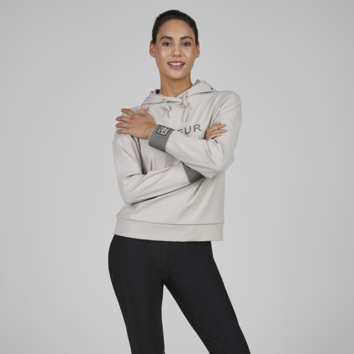 Woman wears pale grey hoodie on soft grey background