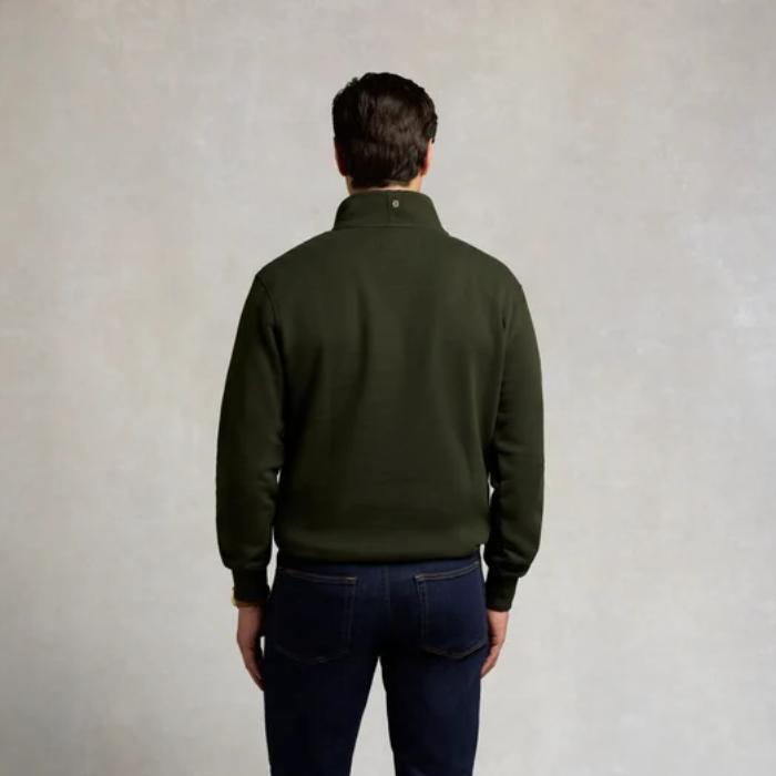 Holland Cooper Classic Quarter Zip Sweat (Men's) Variant Colour Racing Green. A male model wearing a green coloured sweater and blue jeans on grey background.
