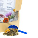 Scoop of dried herbs with floral packaging on a white background