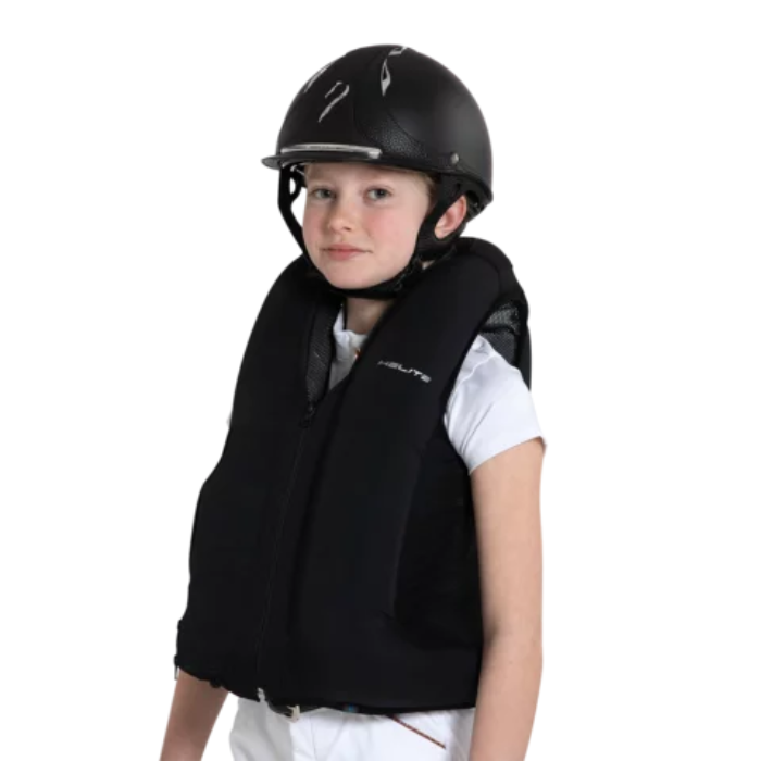 Person wearing a black equestrian vest and helmet on a white background