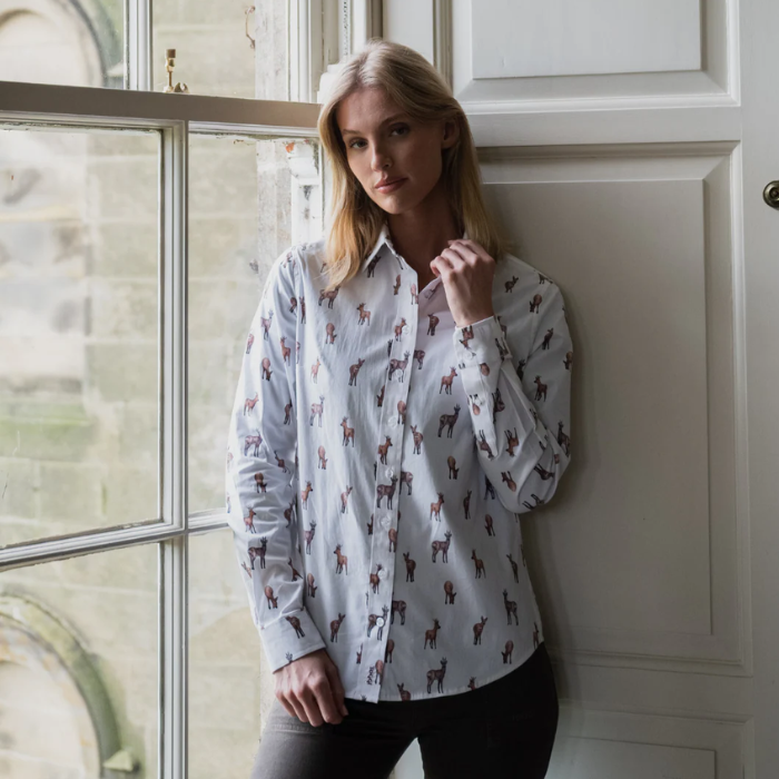 Woman wearing a patterned shirt standing in a room with a window and door.