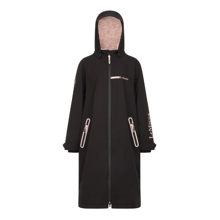 LeMieux AW26 Young Rider HydroShield Robe Varient Black. A black hooded raincoat with a full front zipper, zippered hand pockets, and light pink branding text on the chest and sleeve, displayed on a clean white background.