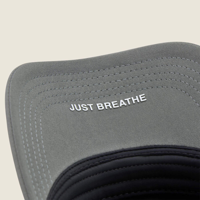 Under rim of grey baseball cap with 'Just Breathe' in white writing