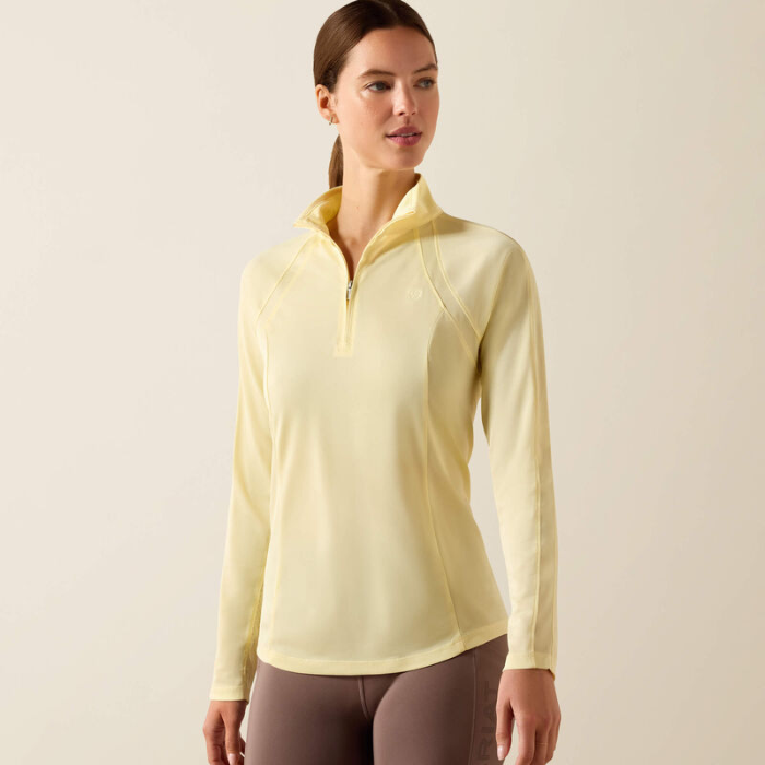 Woman wears a yellow long sleeve top on a beige background