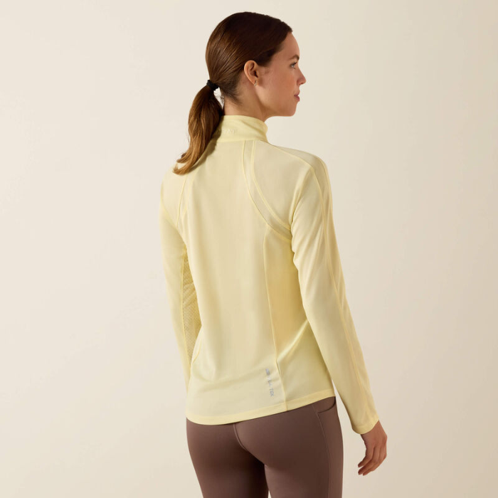 Woman wears a yellow long sleeve top on a beige background