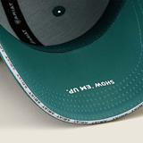 Green baseball cap with SHOW 'EM UP printed on a beige background