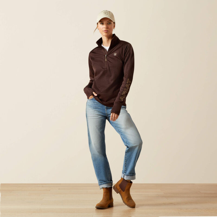 Person wearing a brown jacket, blue jeans, and brown boots on a plain background