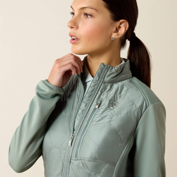 Woman wearing a light green quilted jacket against a beige background