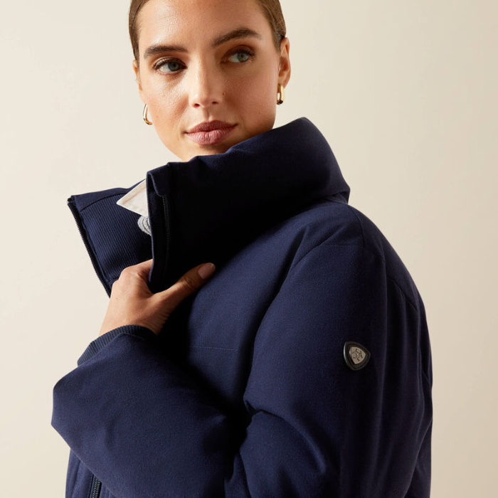 Woman wearing a navy blue coat against a beige background