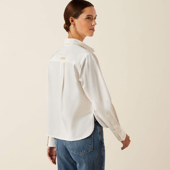 Woman wearing a white shirt and blue jeans on a beige background