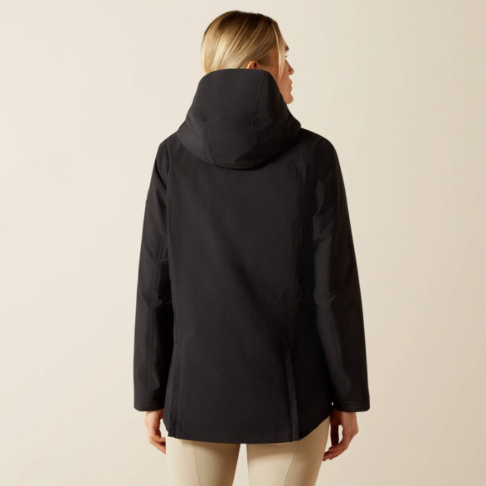 Person wearing a black hooded jacket on a beige background