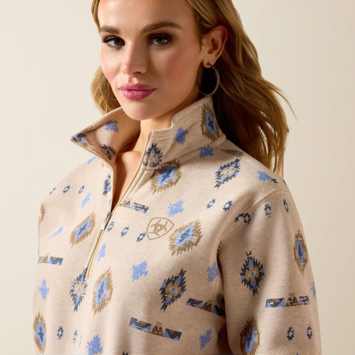 Woman wears a light beige sweatshirt with western pattern on a plain background