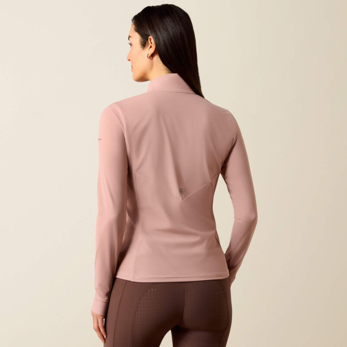 Soft pink riding top with brown leggings on a beige background